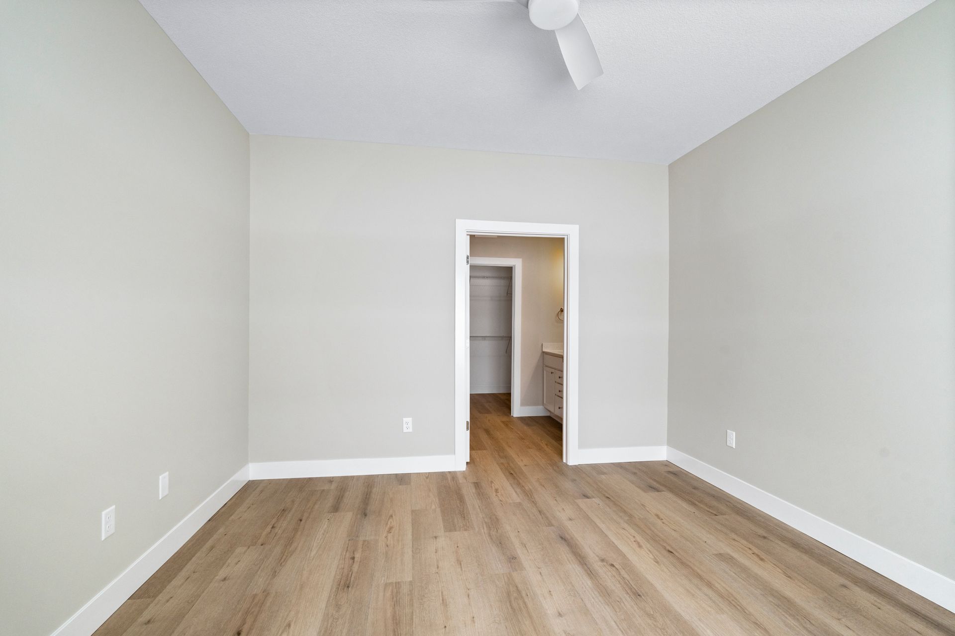 Empty room with light wood floor, white walls and ceiling, doorway to a closet.