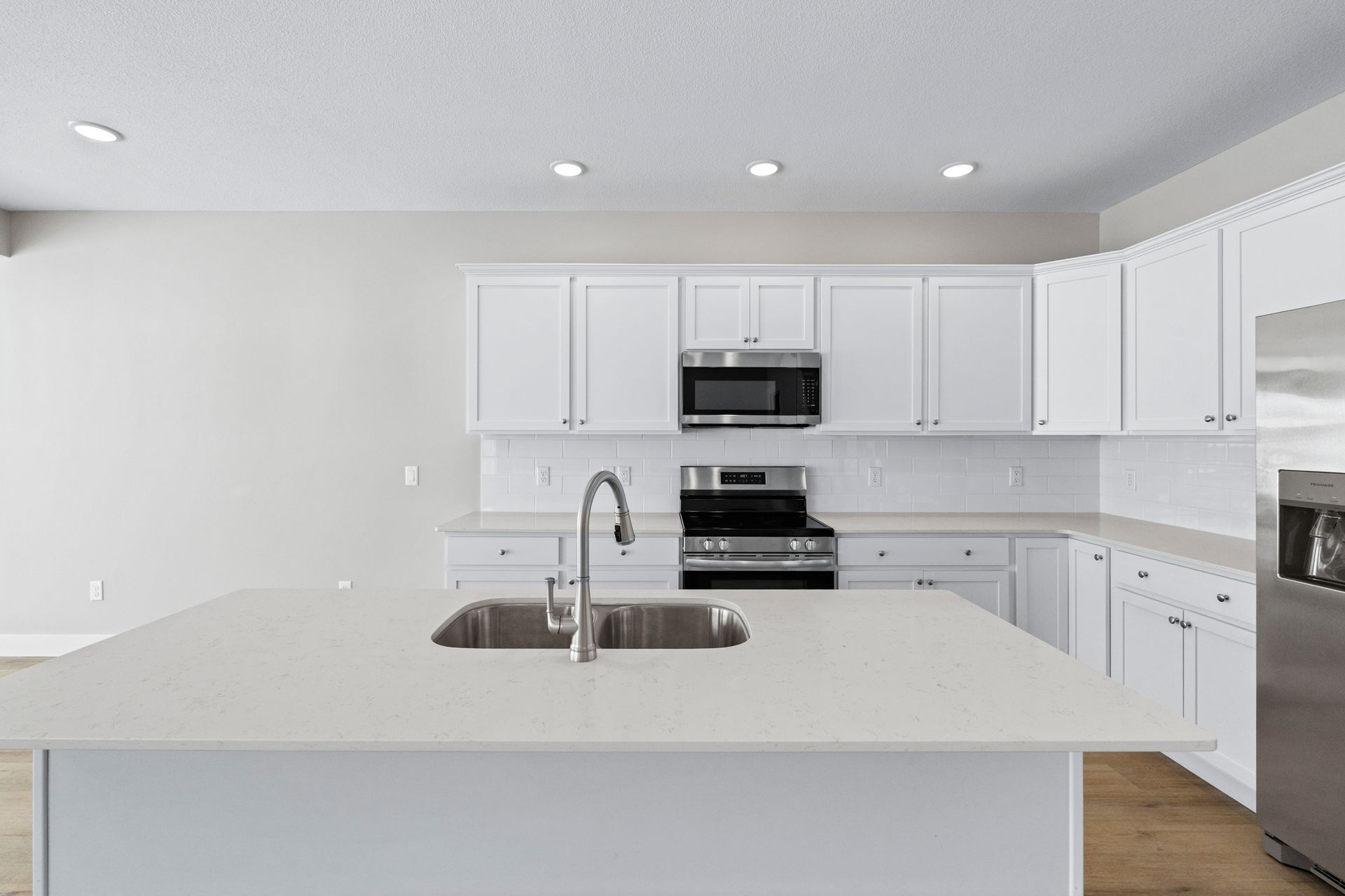 White kitchen with island, cabinets, appliances, and sink.