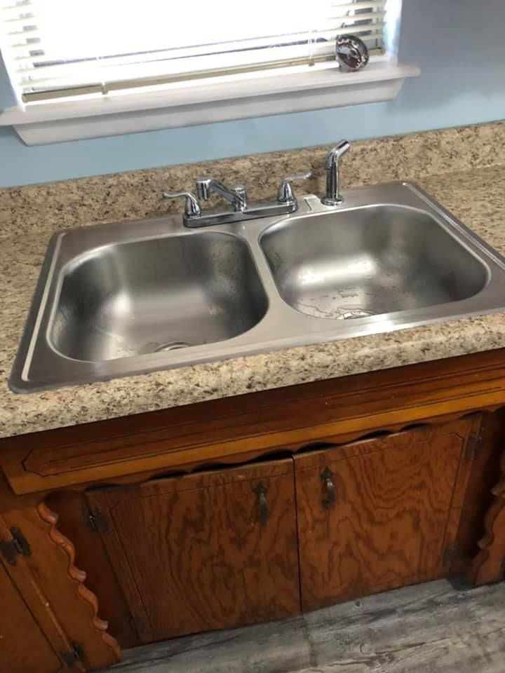 A stainless steel kitchen sink is sitting on top of a wooden counter.