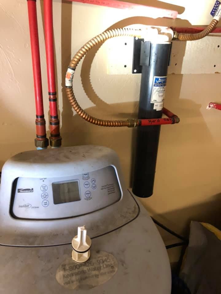 A water softener is sitting in a room next to a hose.