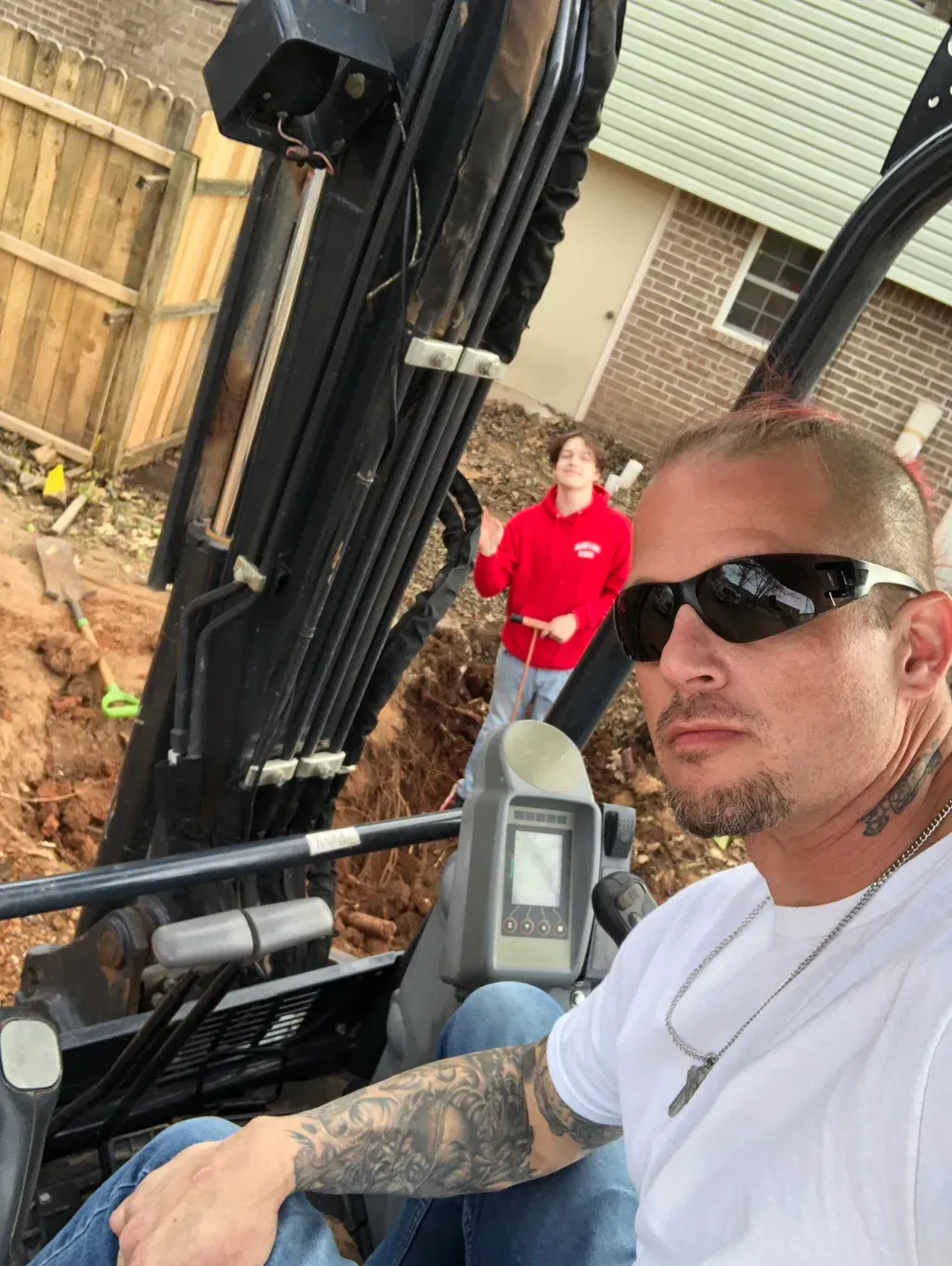 A man wearing sunglasses is sitting in a construction vehicle.