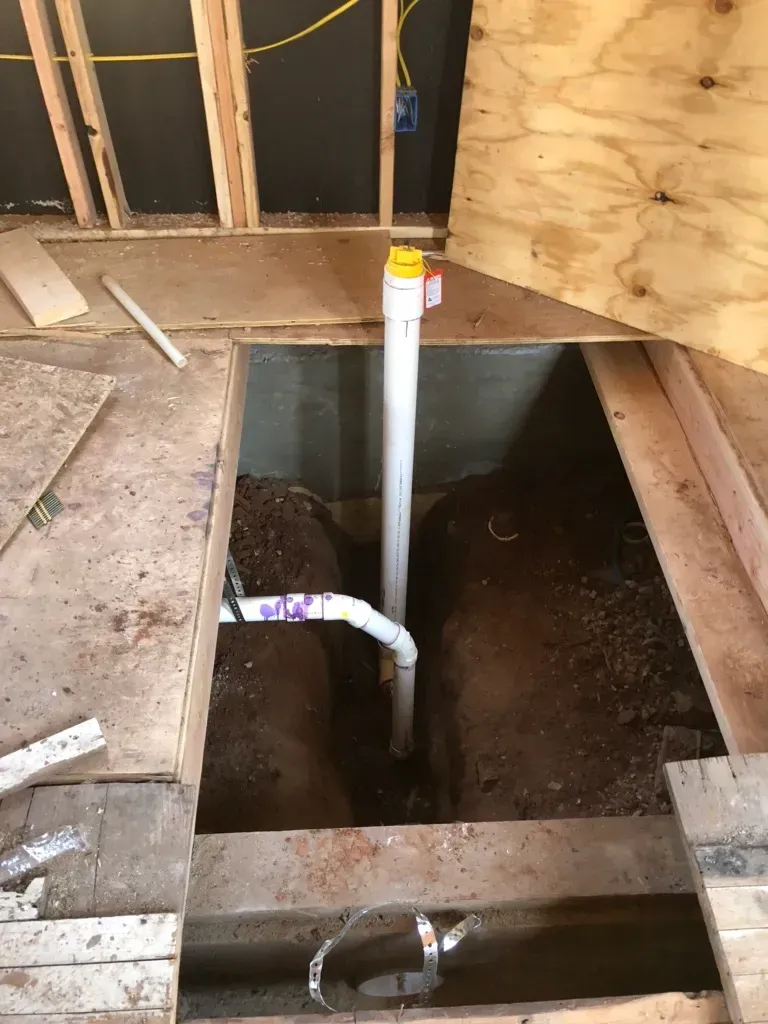 A pipe is being installed in a hole in the floor.