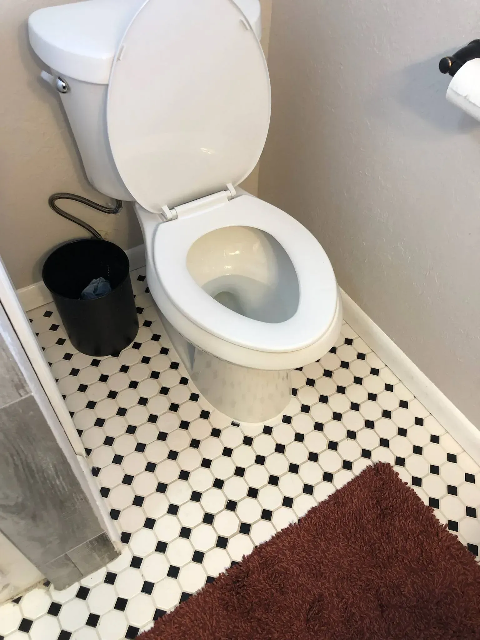 A toilet is sitting on a tiled floor in a bathroom.