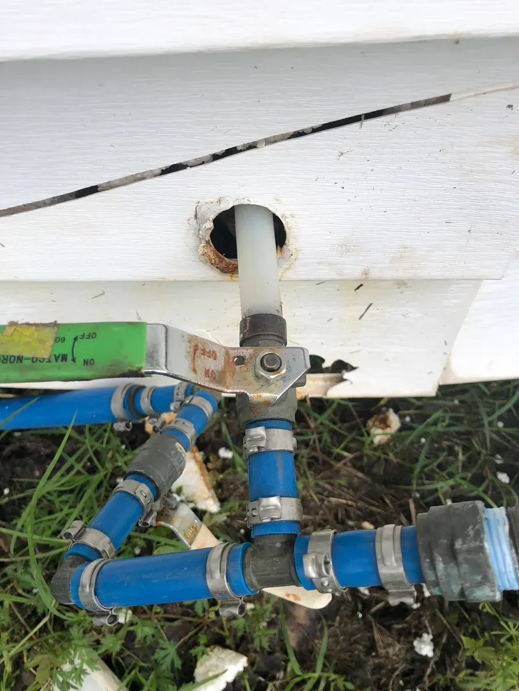 A blue pipe is connected to a white wall.