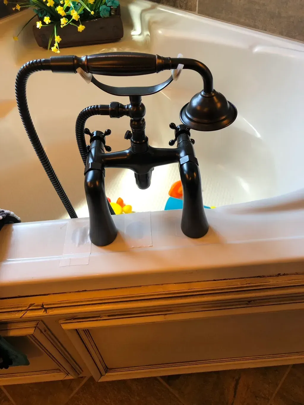 A black bathtub faucet with a hose attached to it