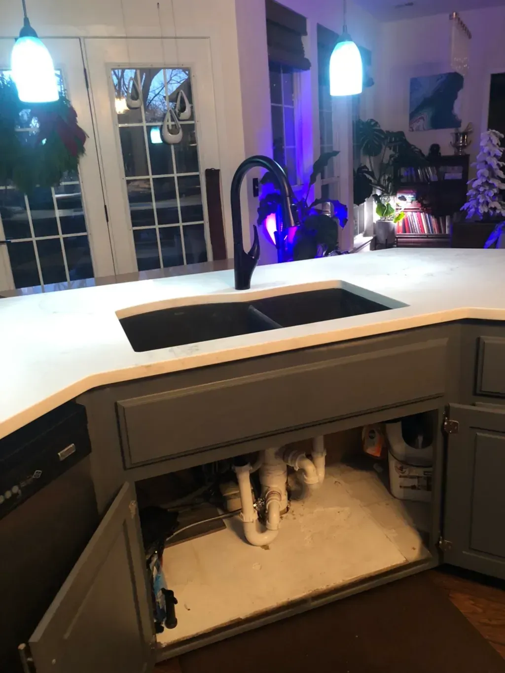 A kitchen with a sink and cabinets open