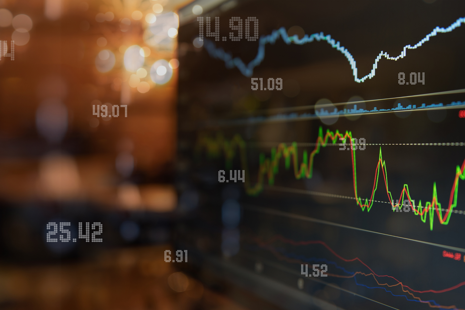 Stock market graph on a computer screen with data and fluctuating lines, set against a blurred background.