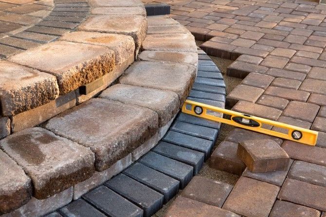 Level laid across curved stone steps and pavers, showing uneven brickwork alignment