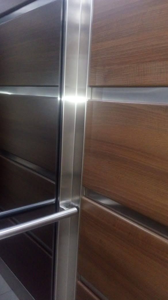 Un primer plano de una puerta de ascensor de acero inoxidable y madera.