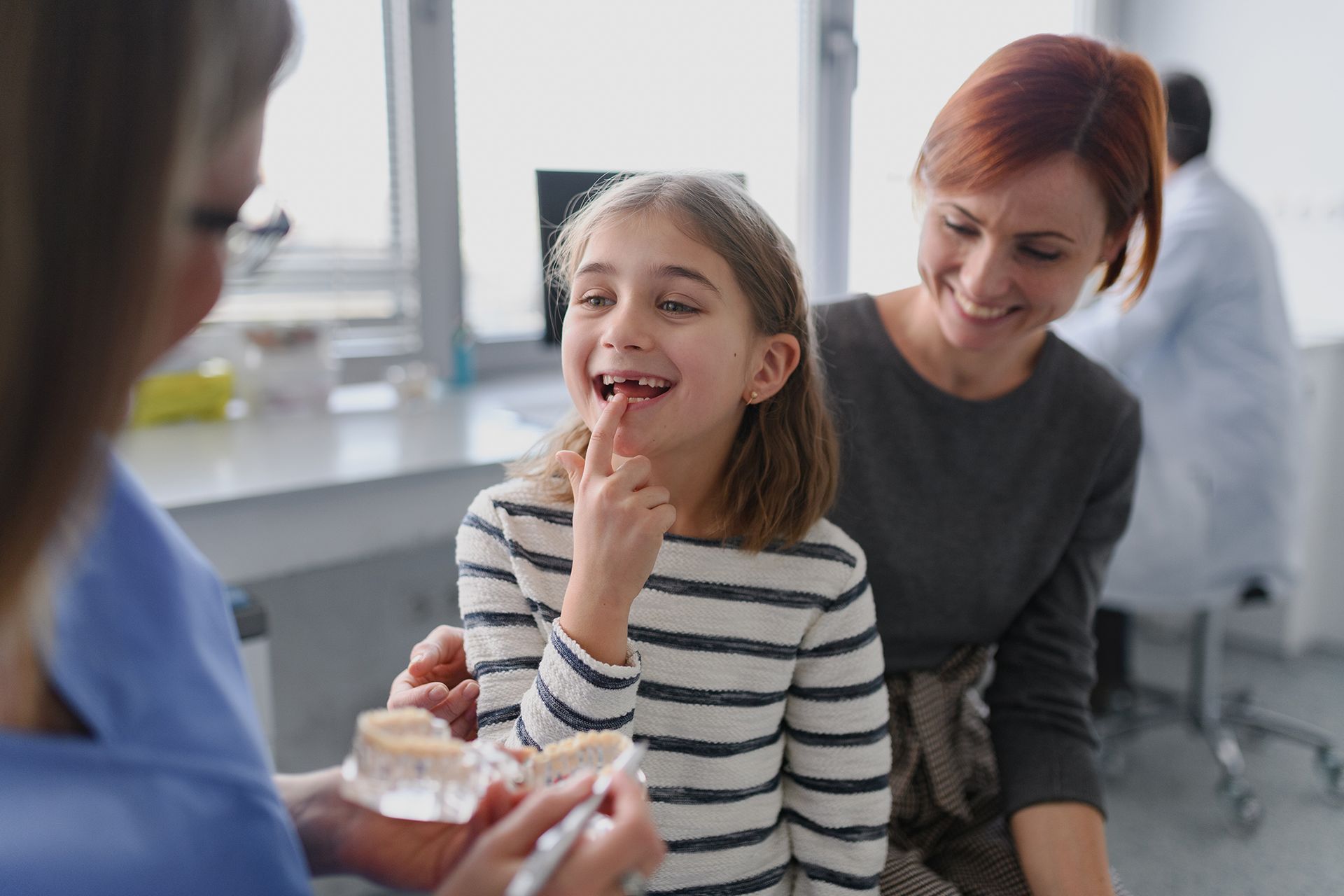 A girl showing her lost tooth to a dentist during a routine checkup at a dental clinic.
