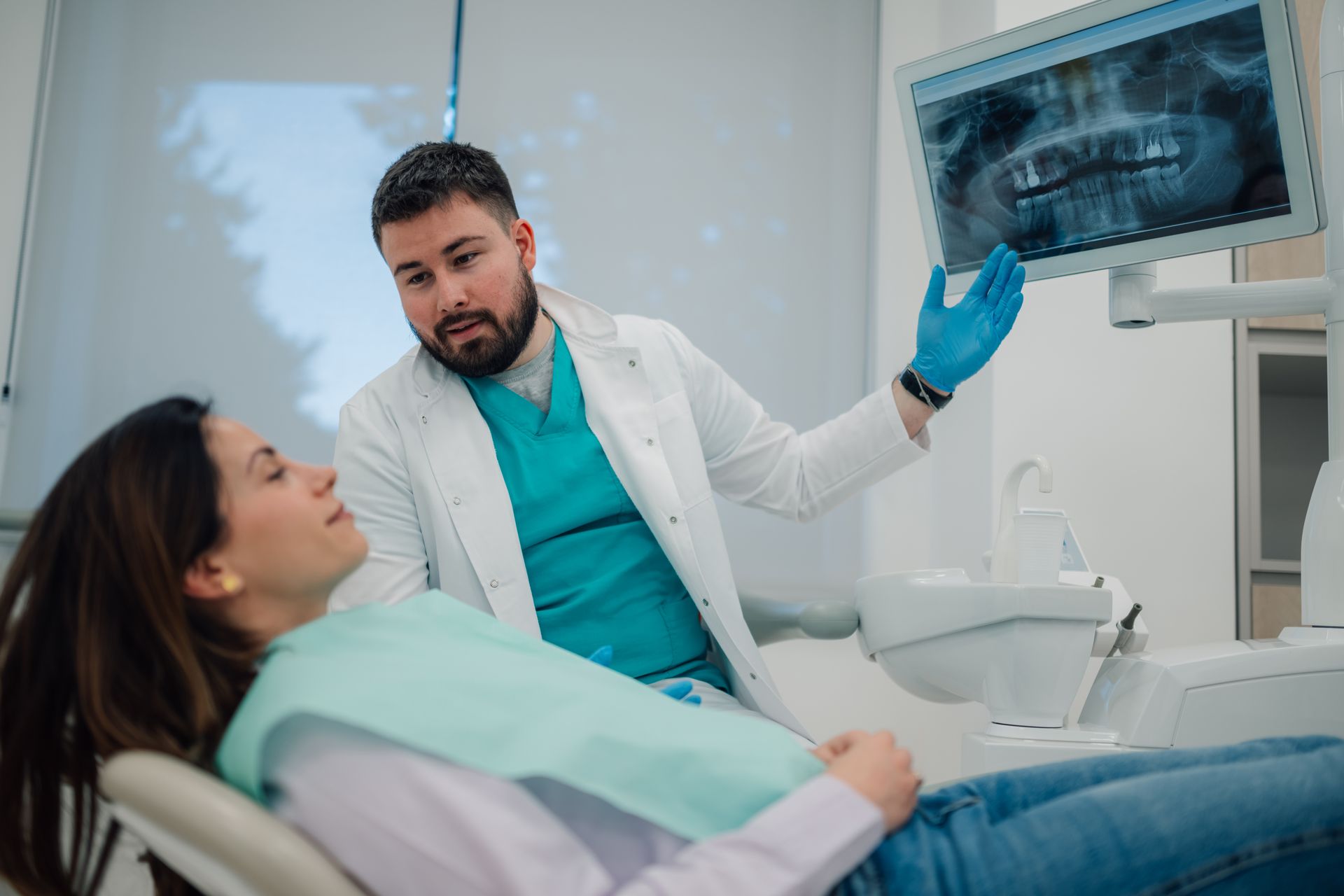 A restorative dentist reviewing a dental X-ray with a patient during a consultation.