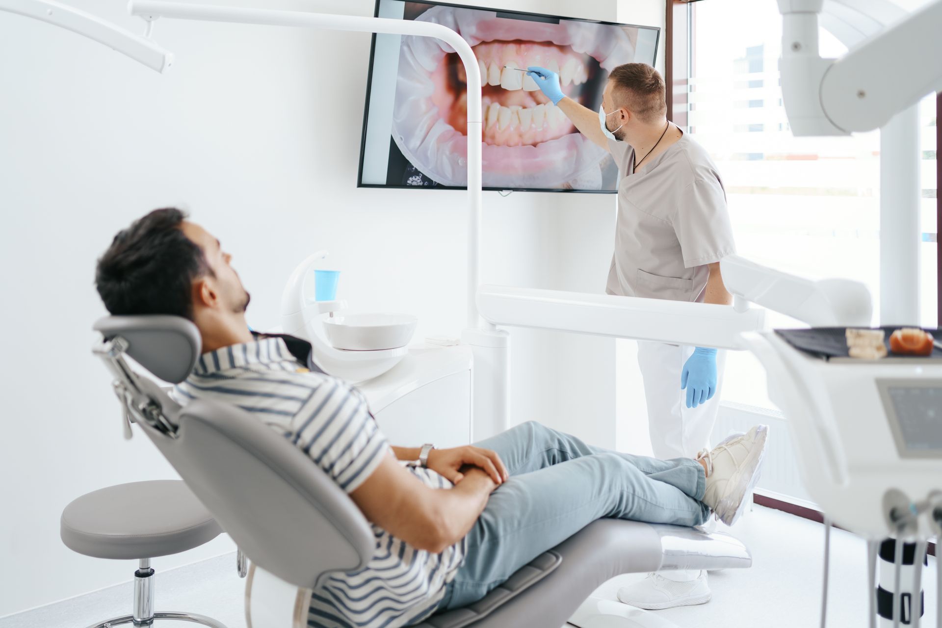 A general dentist providing oral health consultation with visual imagery on screen.
