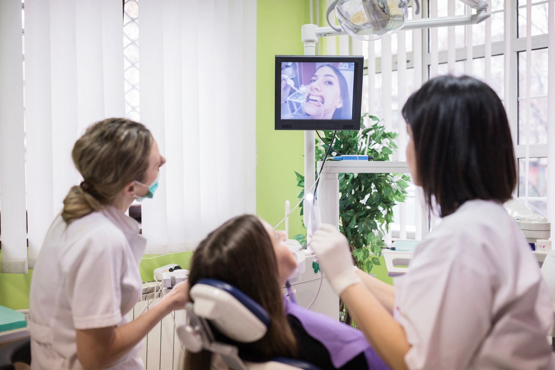 A woman is sitting at a table talking to a dentist while looking at a computer screen.Dotted Background