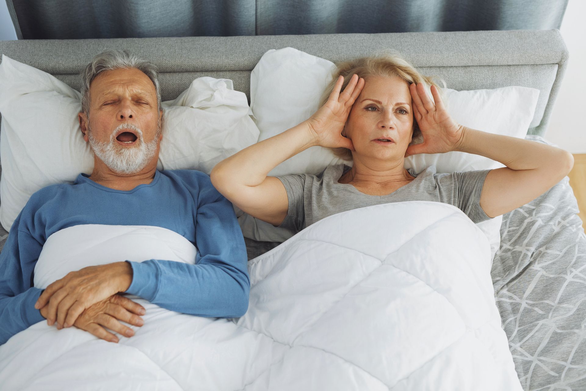 A man wearing a cpap mask is stretching on a bed.