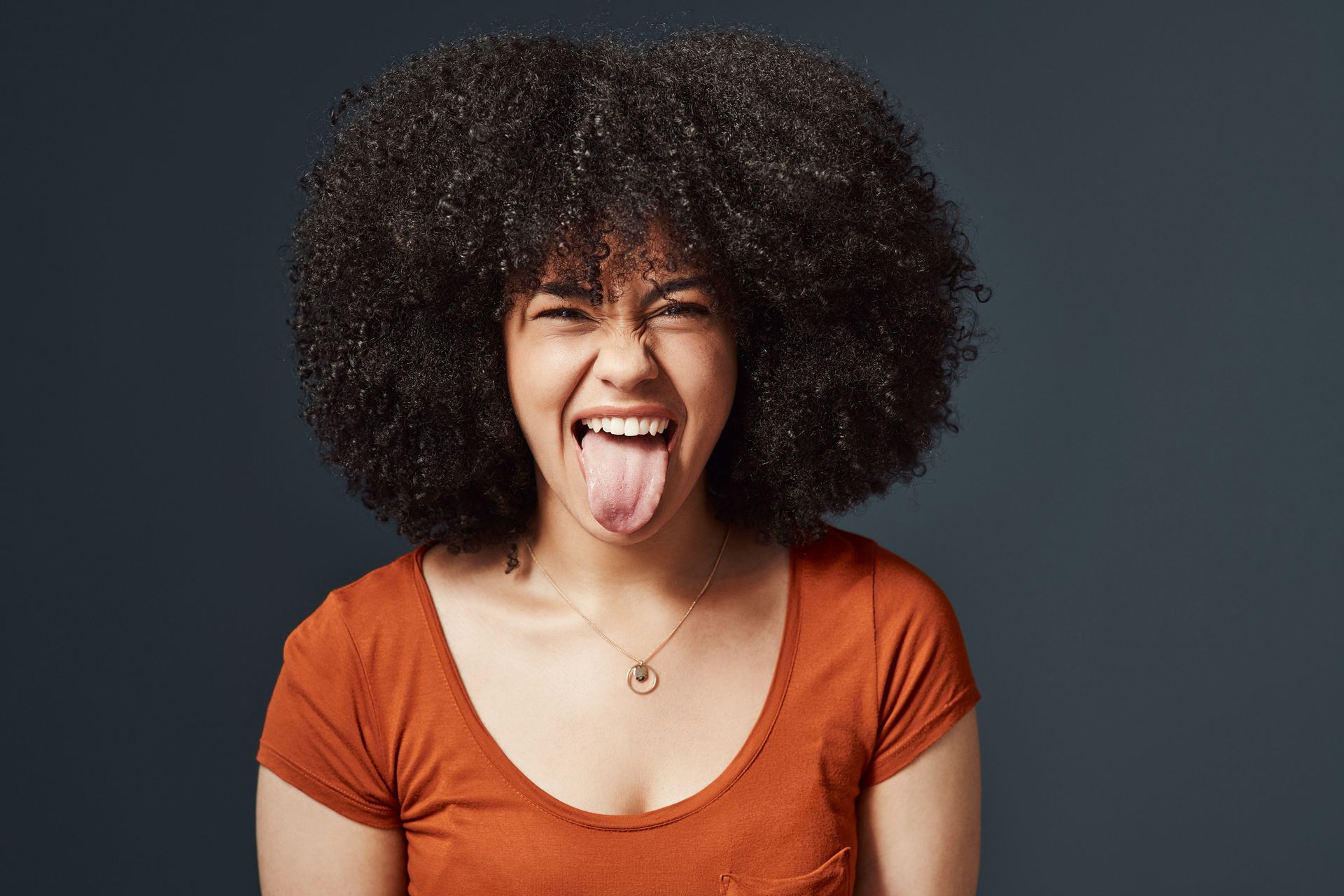 A woman with an afro is sticking her tongue out.