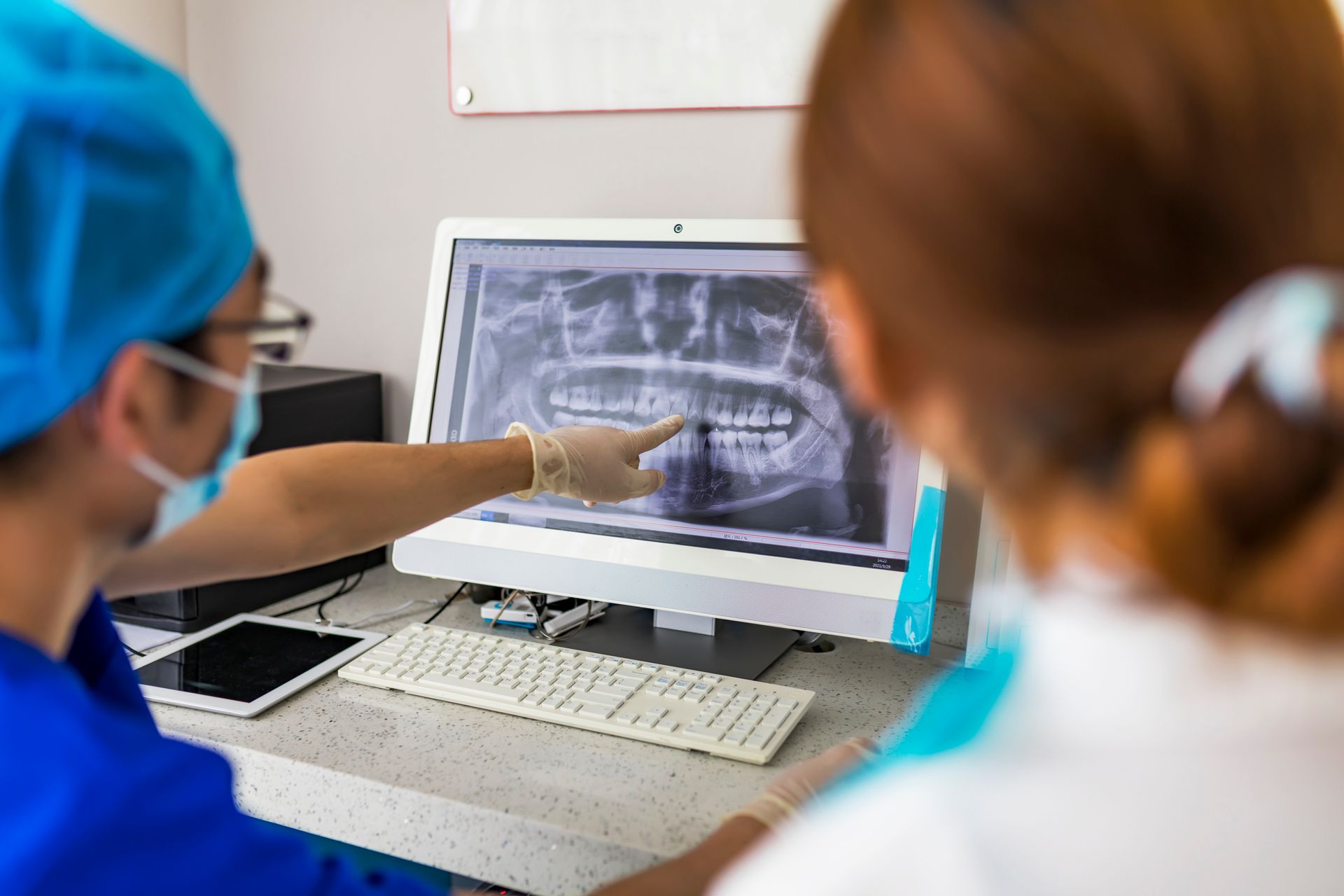 A dentist and a nurse are looking at an x-ray on a computer screen.