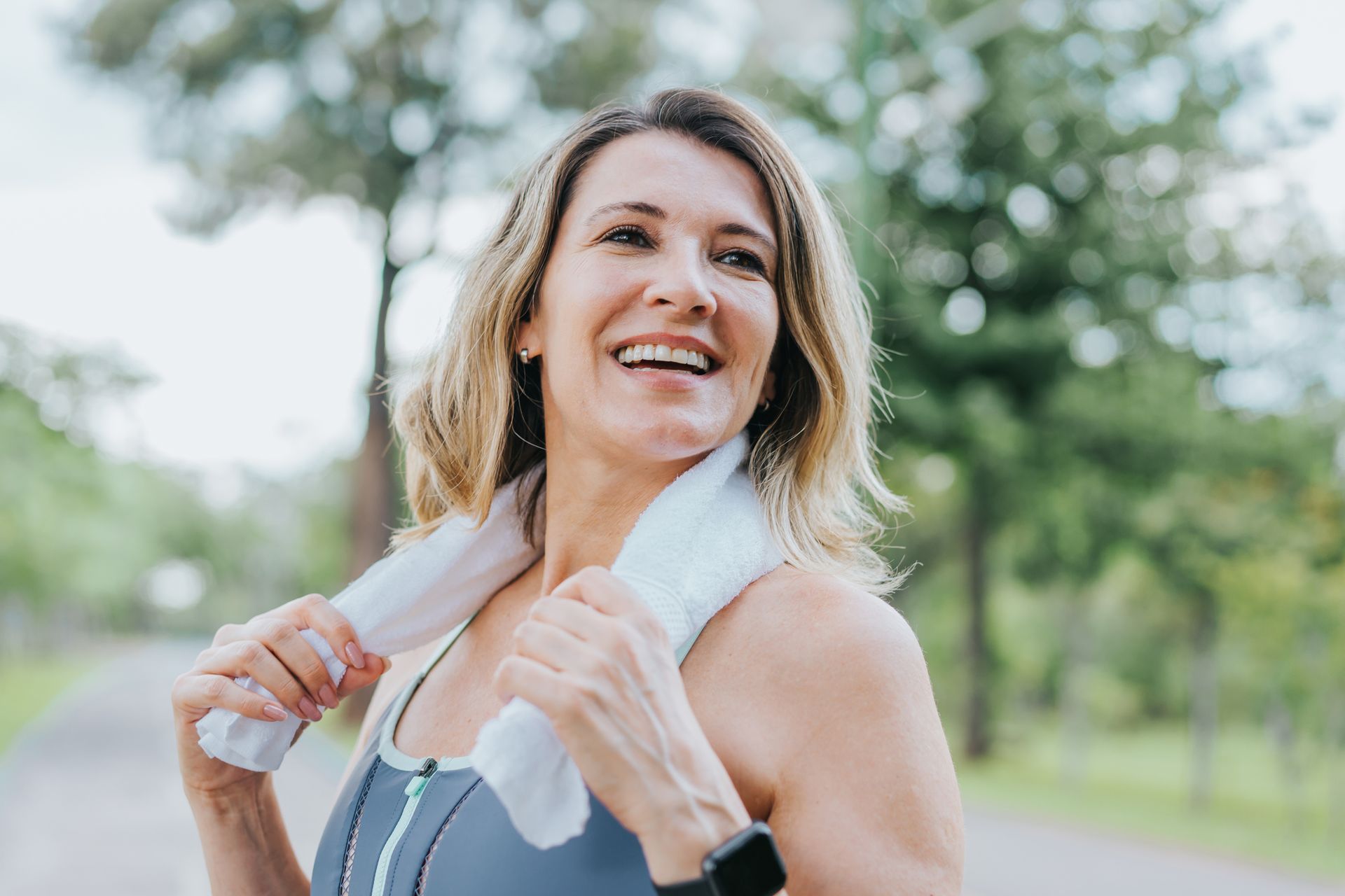 A woman is smiling while holding a towel around her neck.
