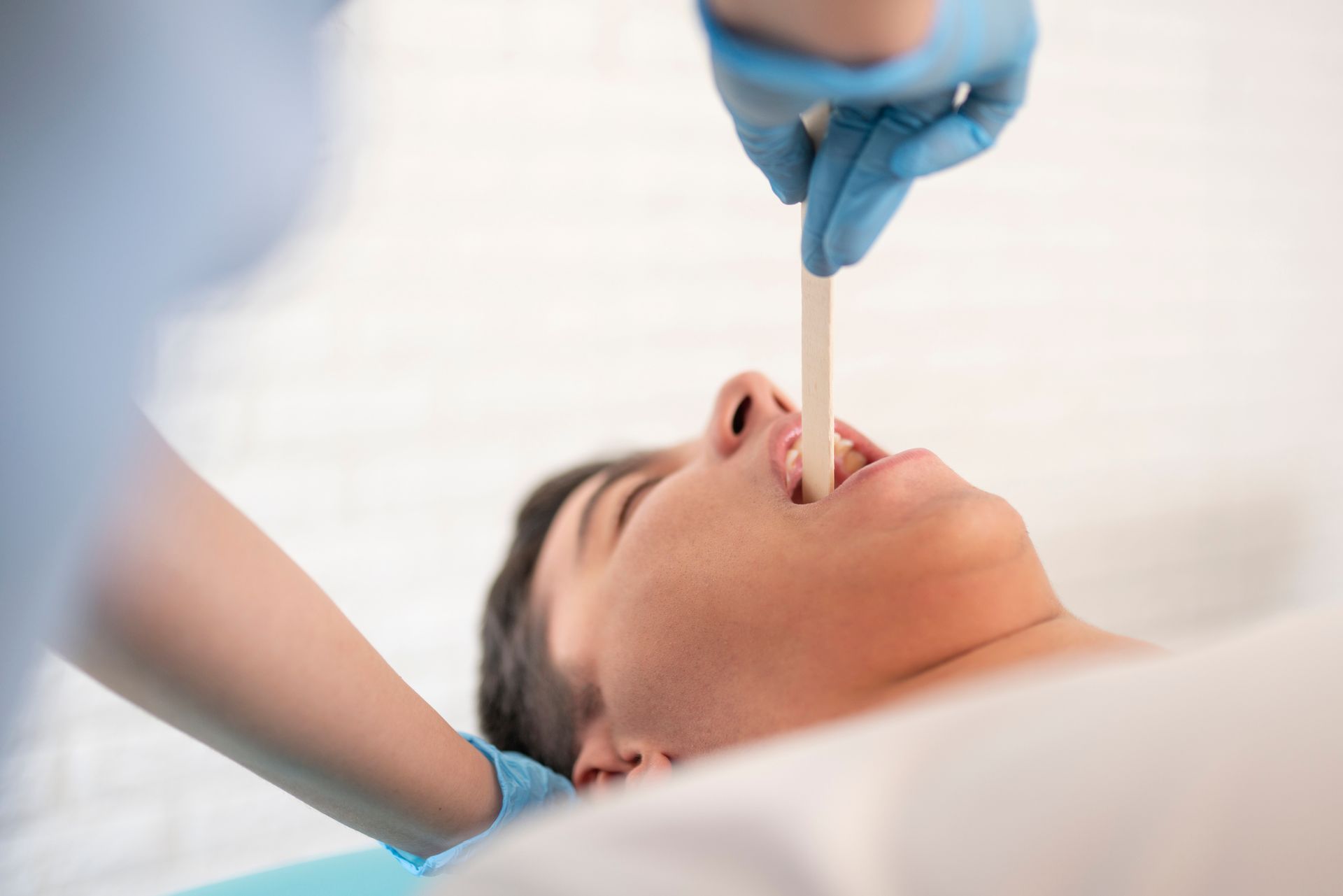 A doctor is examining a patient 's tongue with a tongue depressor.