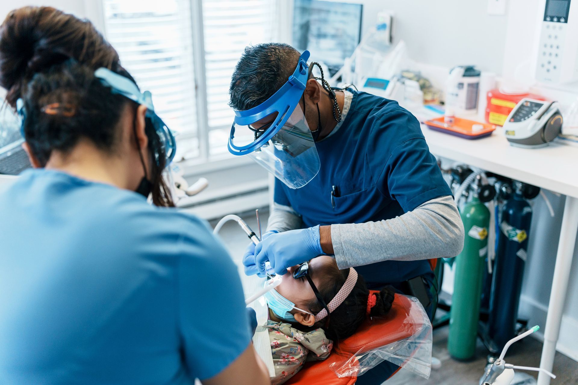 A dentist is examining a child 's teeth in a dental office.