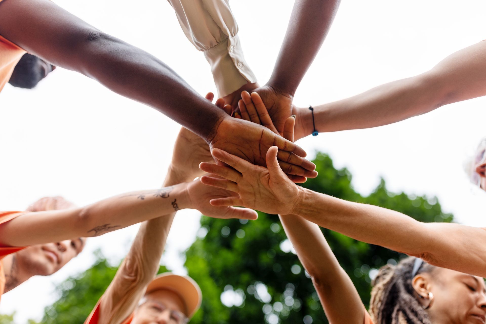 A group of people are putting their hands together in a circle.