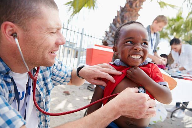 A man is listening to a child 's heart with a stethoscope.