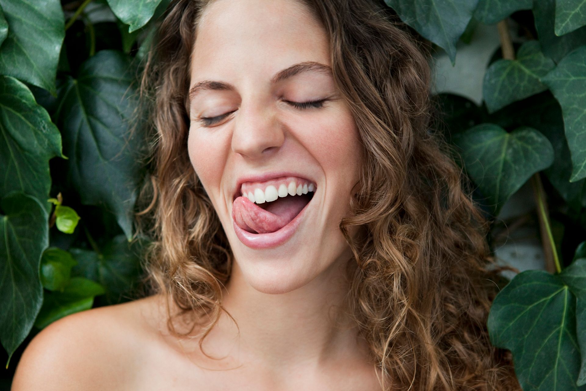 A woman with curly hair is making a funny face with her tongue out.