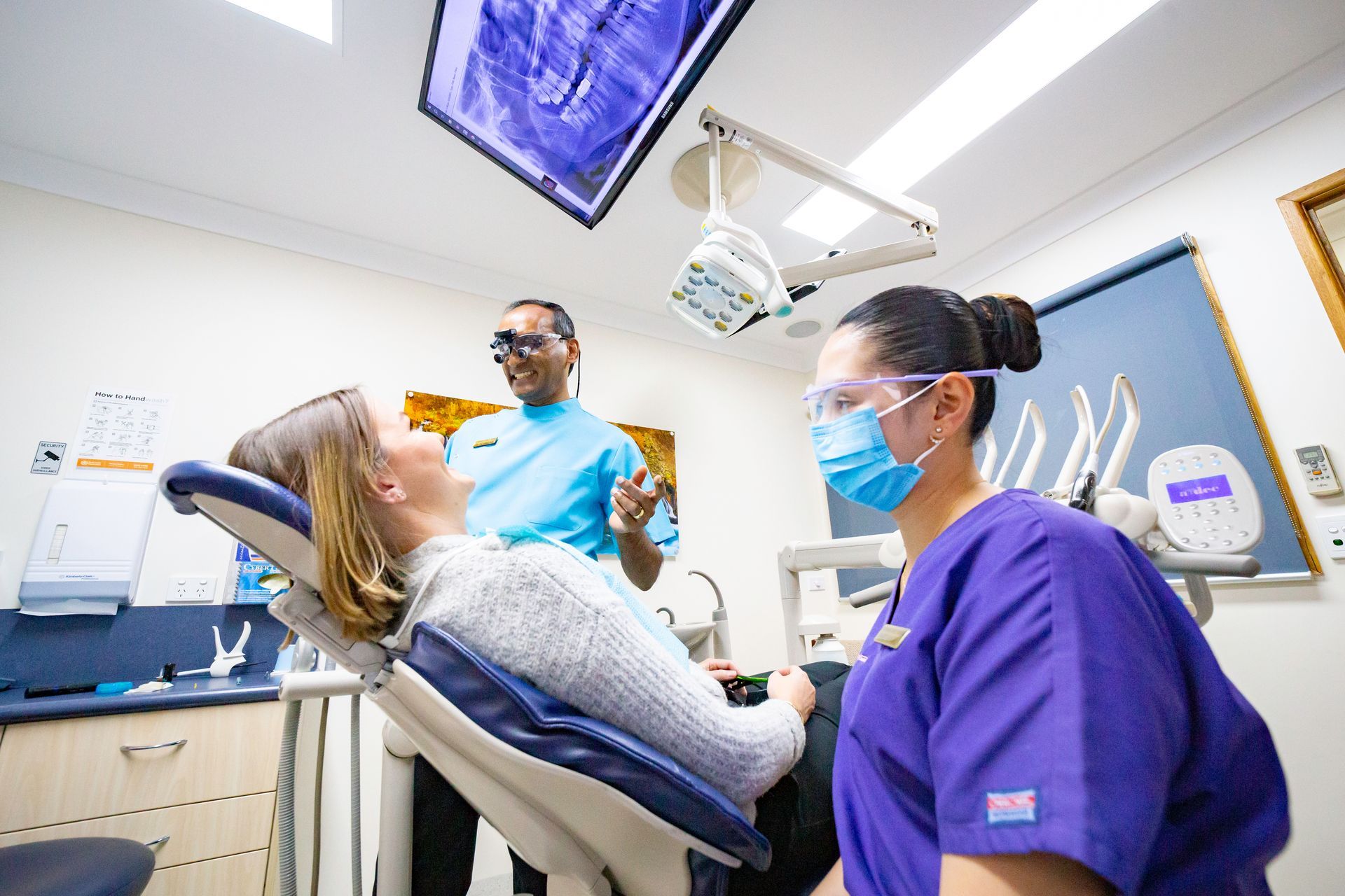 A woman is pointing at her teeth and smiling.