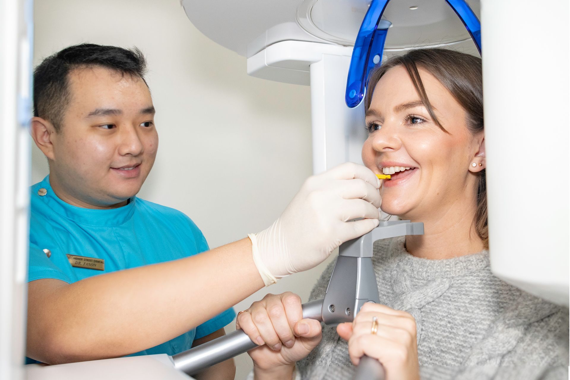 A woman is smiling while getting an x-ray of her teeth.