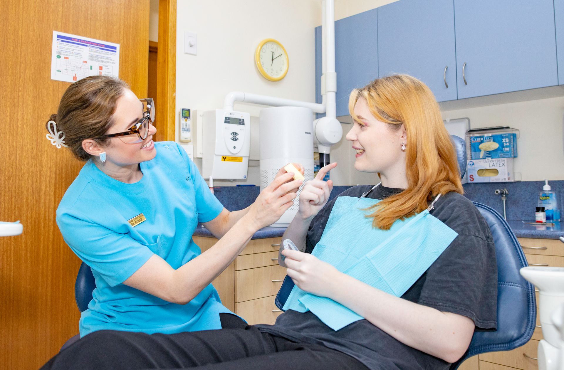 A dentist is holding a model of teeth in her hands.