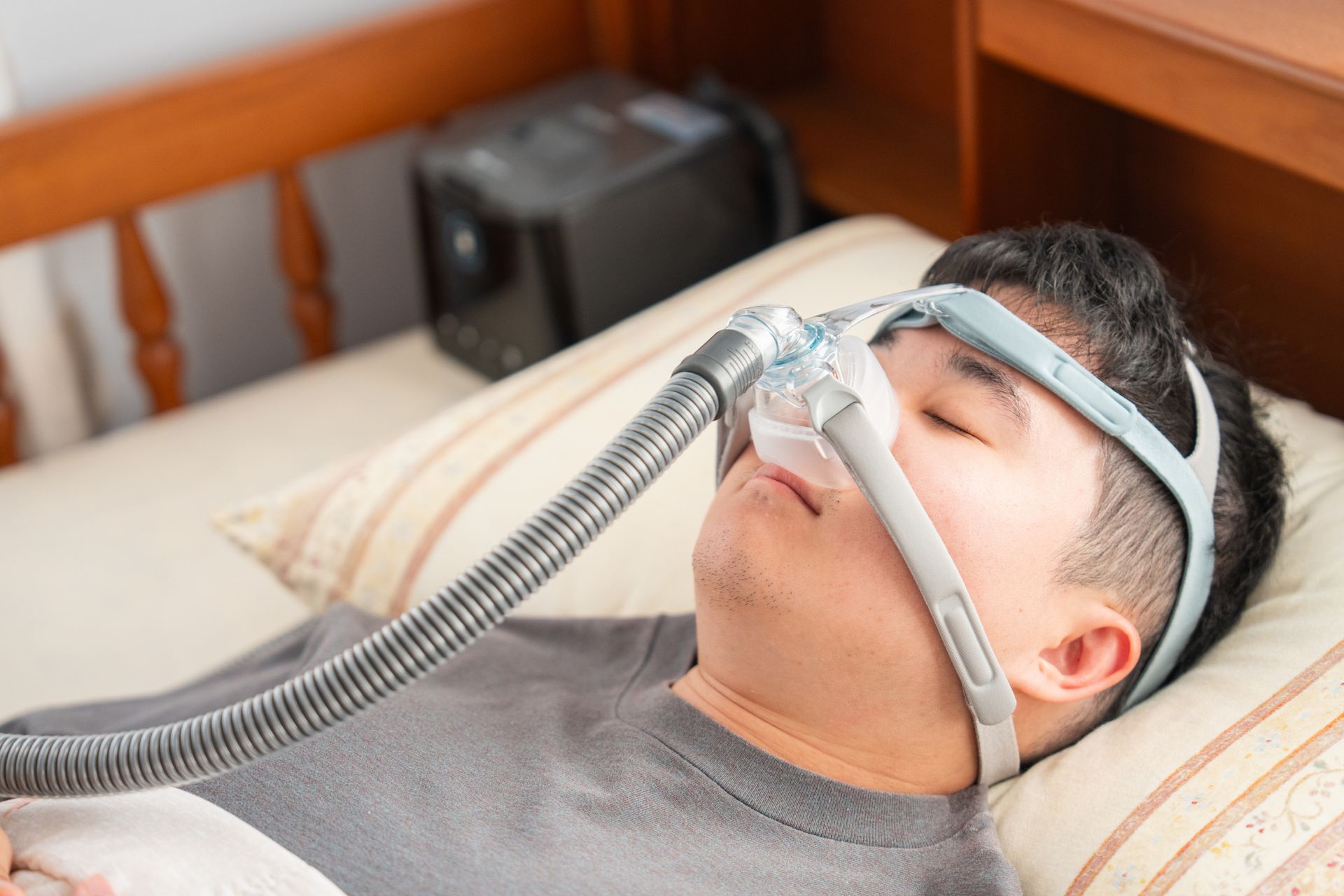 A man is sleeping in a bed with an oxygen mask on his face.