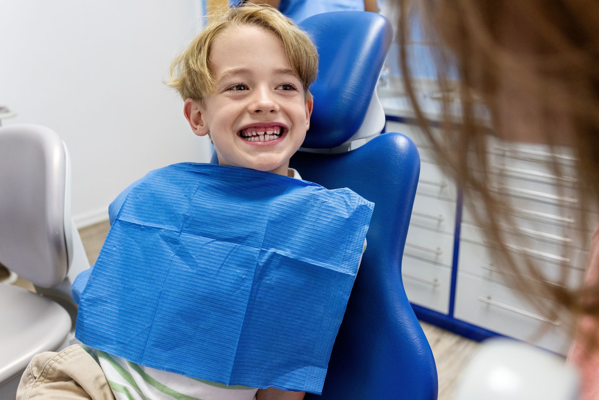 A young boy is smiling while sitting in a dental chair.