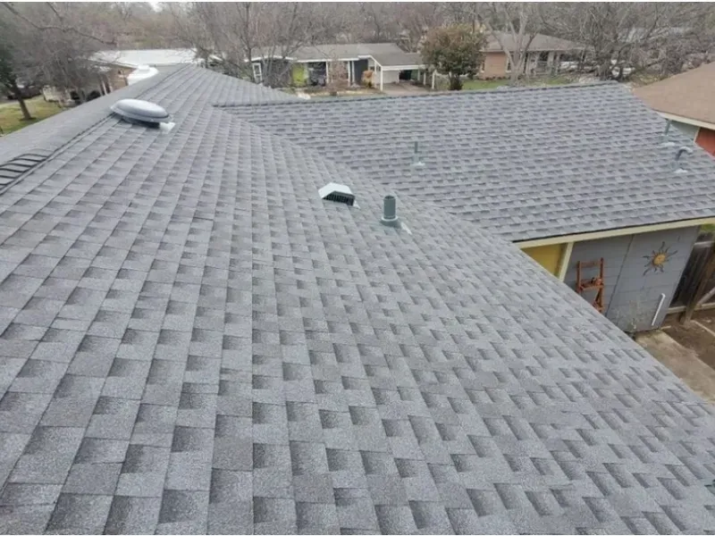 Gray asphalt shingle roof on a house, angled view from above. Skylight and vents visible.