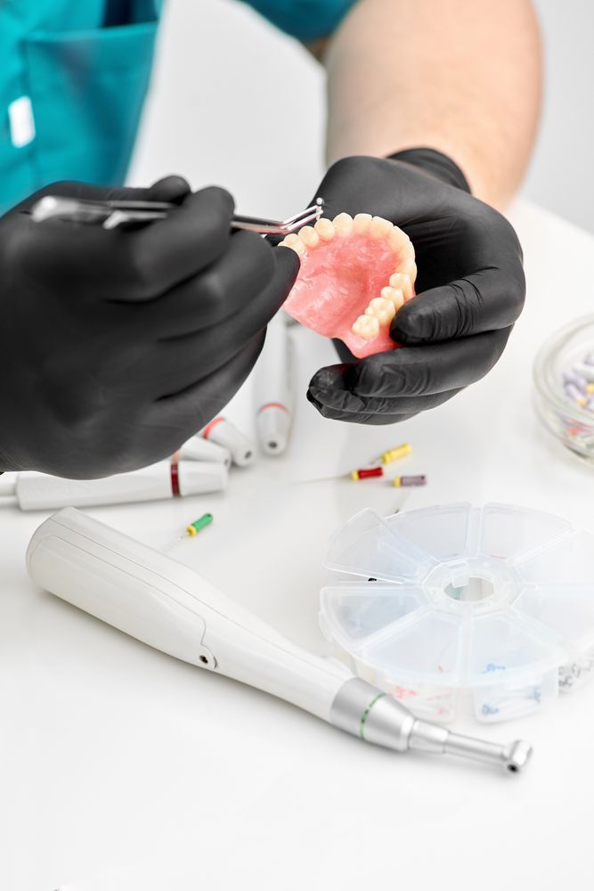 A Dentist is Working on a Denture With a Pair of Scissors — Dental Prosthetics By Richard & Cindy In Oxenford, QLD