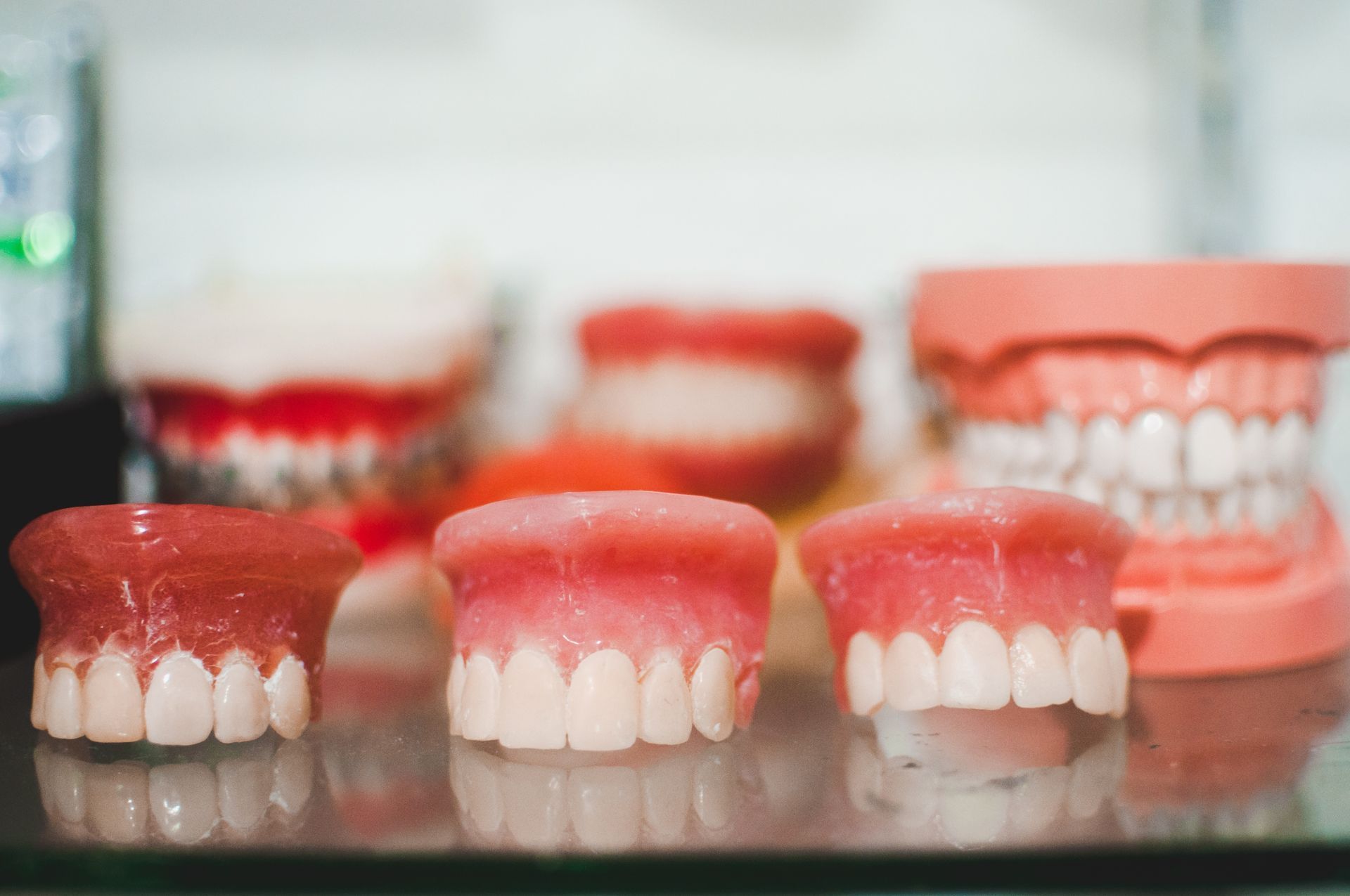 A Group of Dentures Sitting on Top of a Glass Table — Dental Prosthetics By Richard & Cindy In Oxenford, QLD