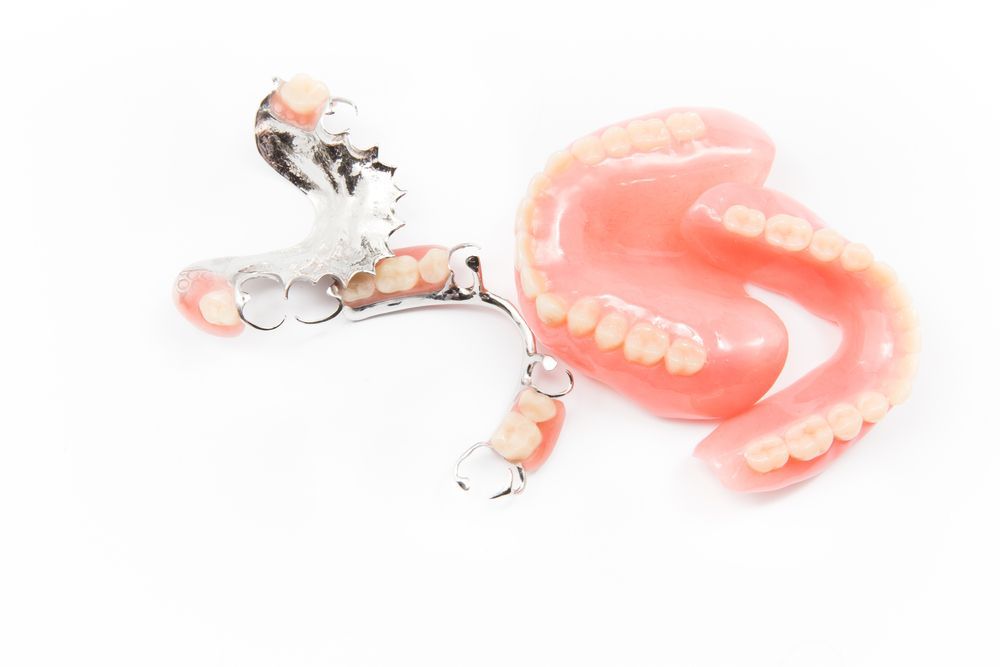 A Pair of Dentures Laying on Top of Each Other on a White Surface — Dental Prosthetics By Richard & Cindy In Oxenford, QLD