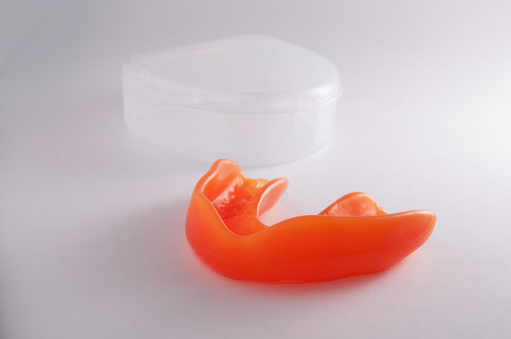 An Orange Mouth Guard is Sitting on a White Surface — Dental Prosthetics By Richard & Cindy In Oxenford, QLD