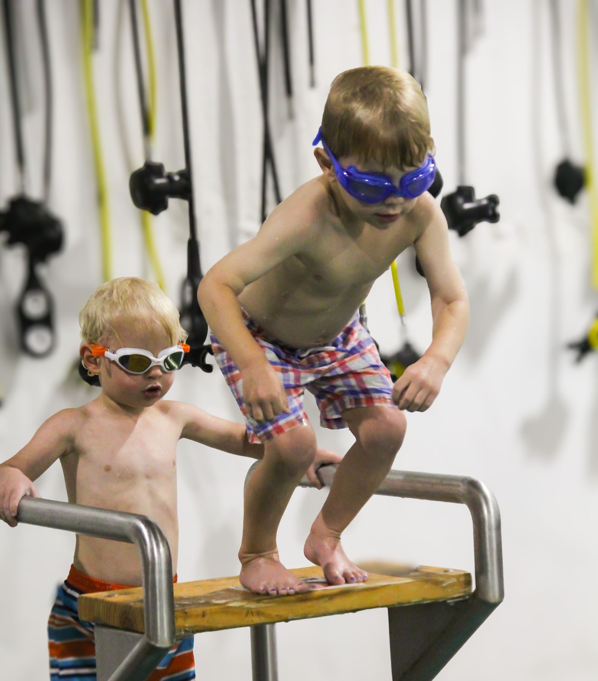 Swimming Lessons wto young boys wearing swim goggles are jumping off a diving board