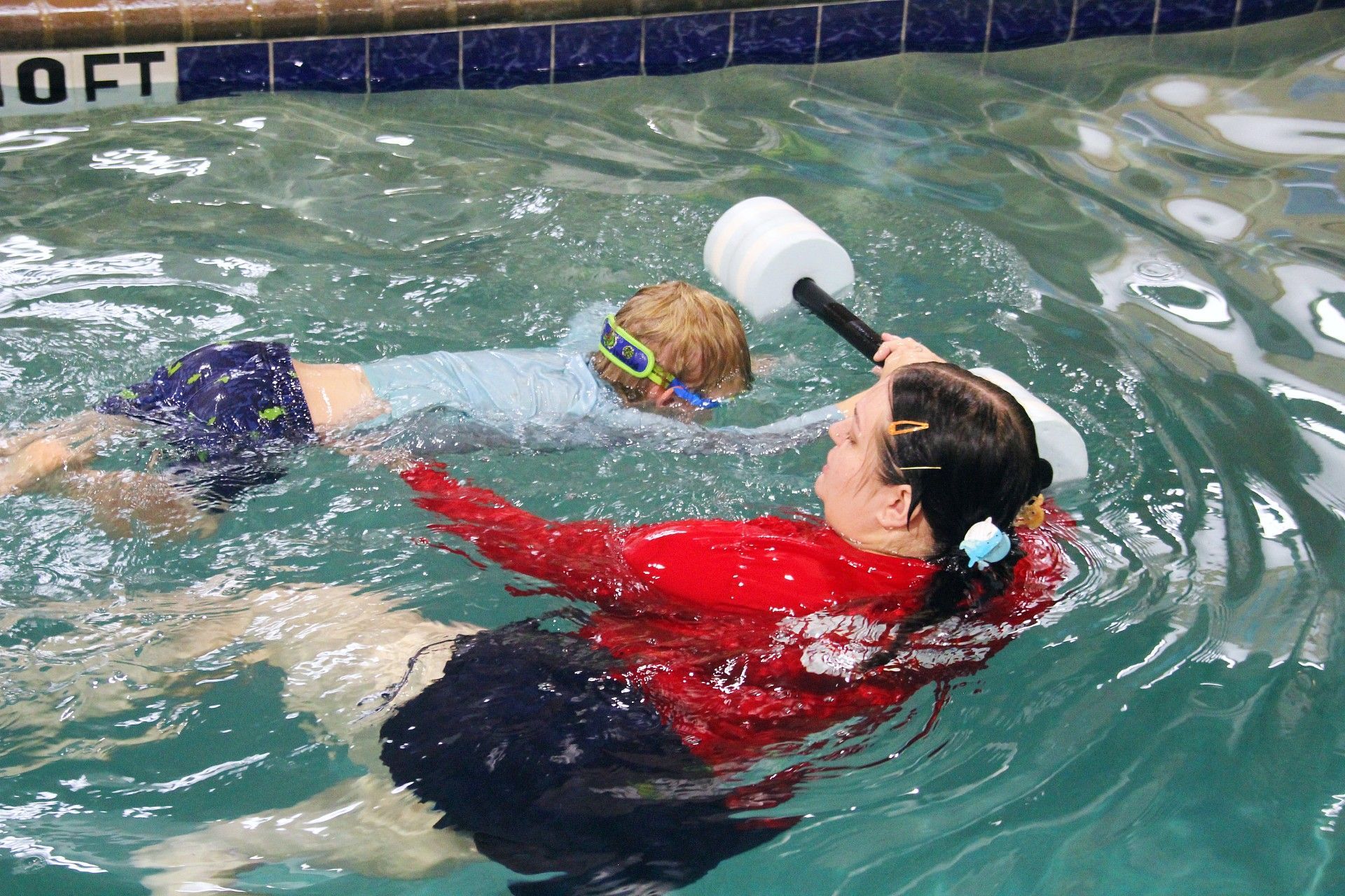 Child's Swimming lessons a young girl in a purple swimsuit practicing diving into a swimming pool