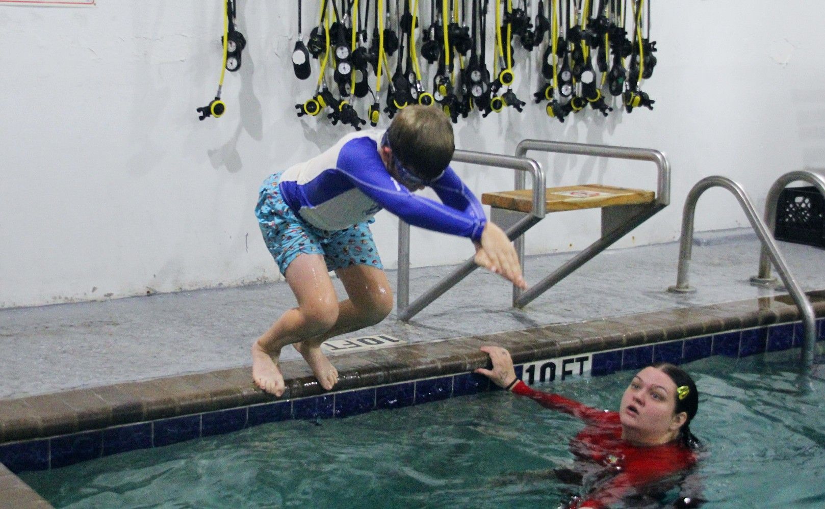 Childs swimming lessons A child is holding a blue board in a swimming pool
