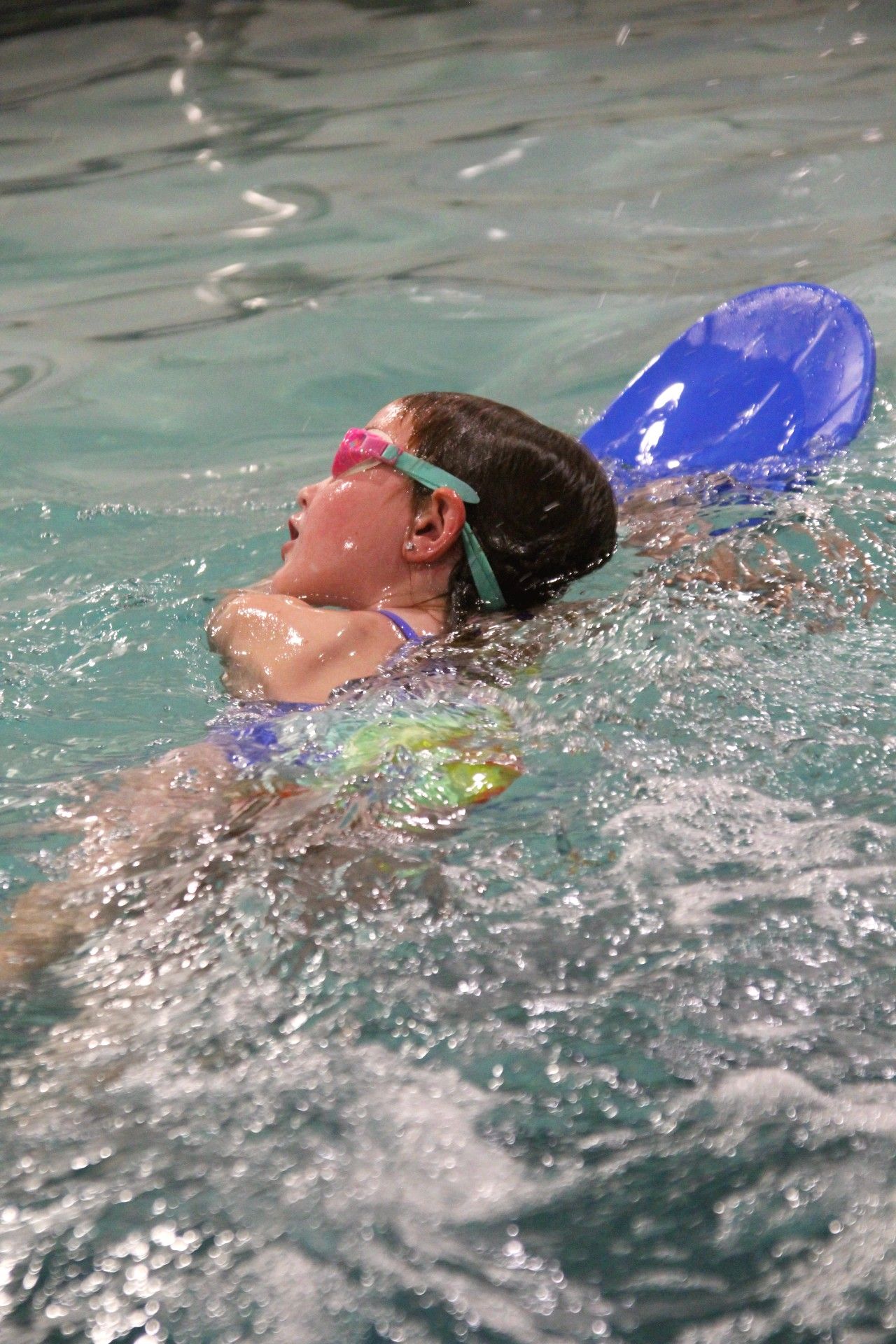 Swimming lessons a young girl is swimming in a pool with a paddle.