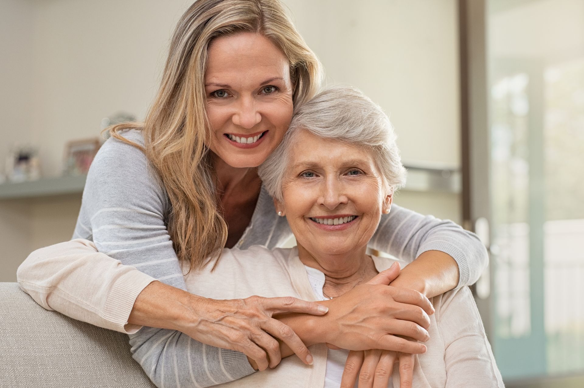 A woman is hugging an older woman on a couch.