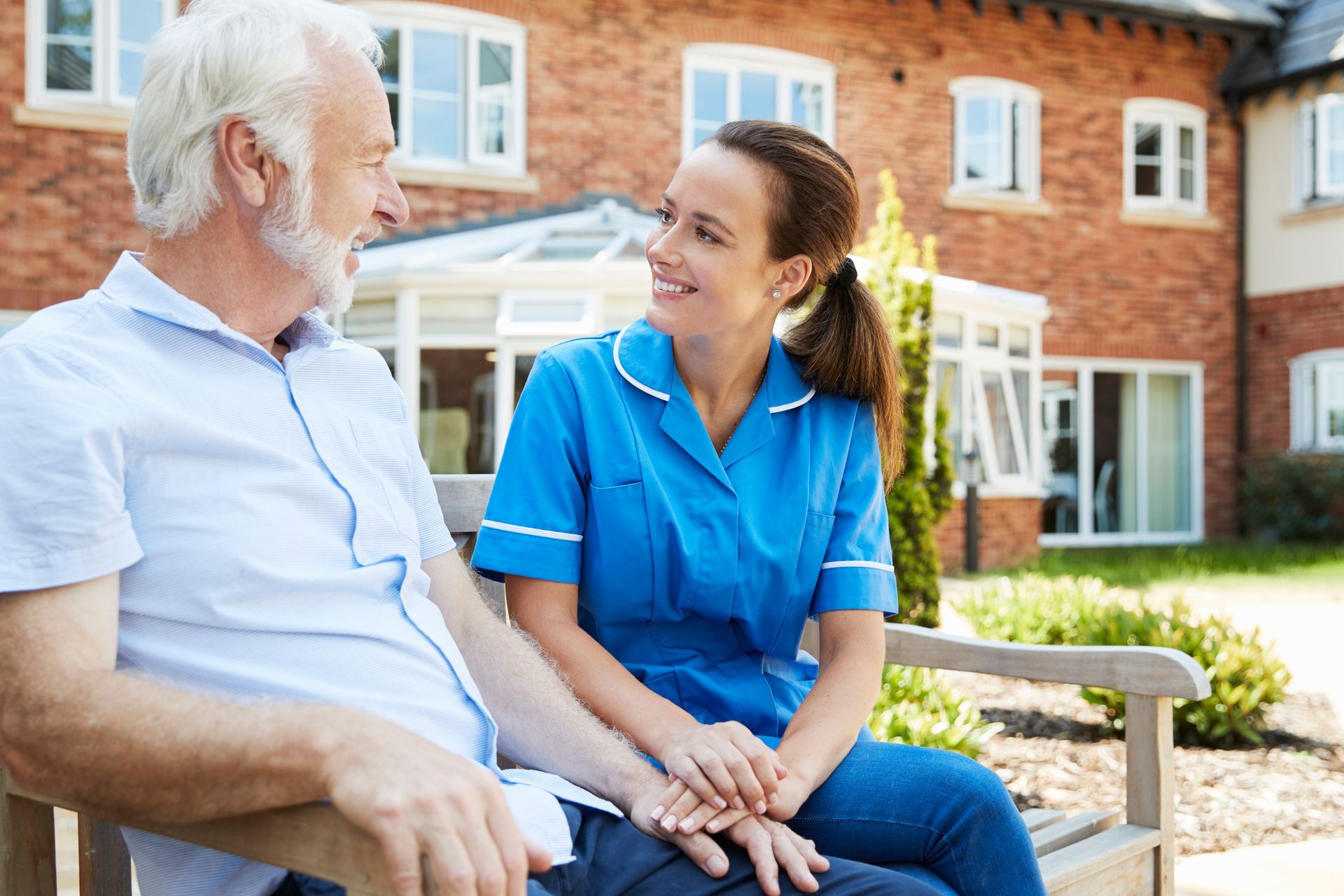 A nurse is sitting on a bench with an elderly man.