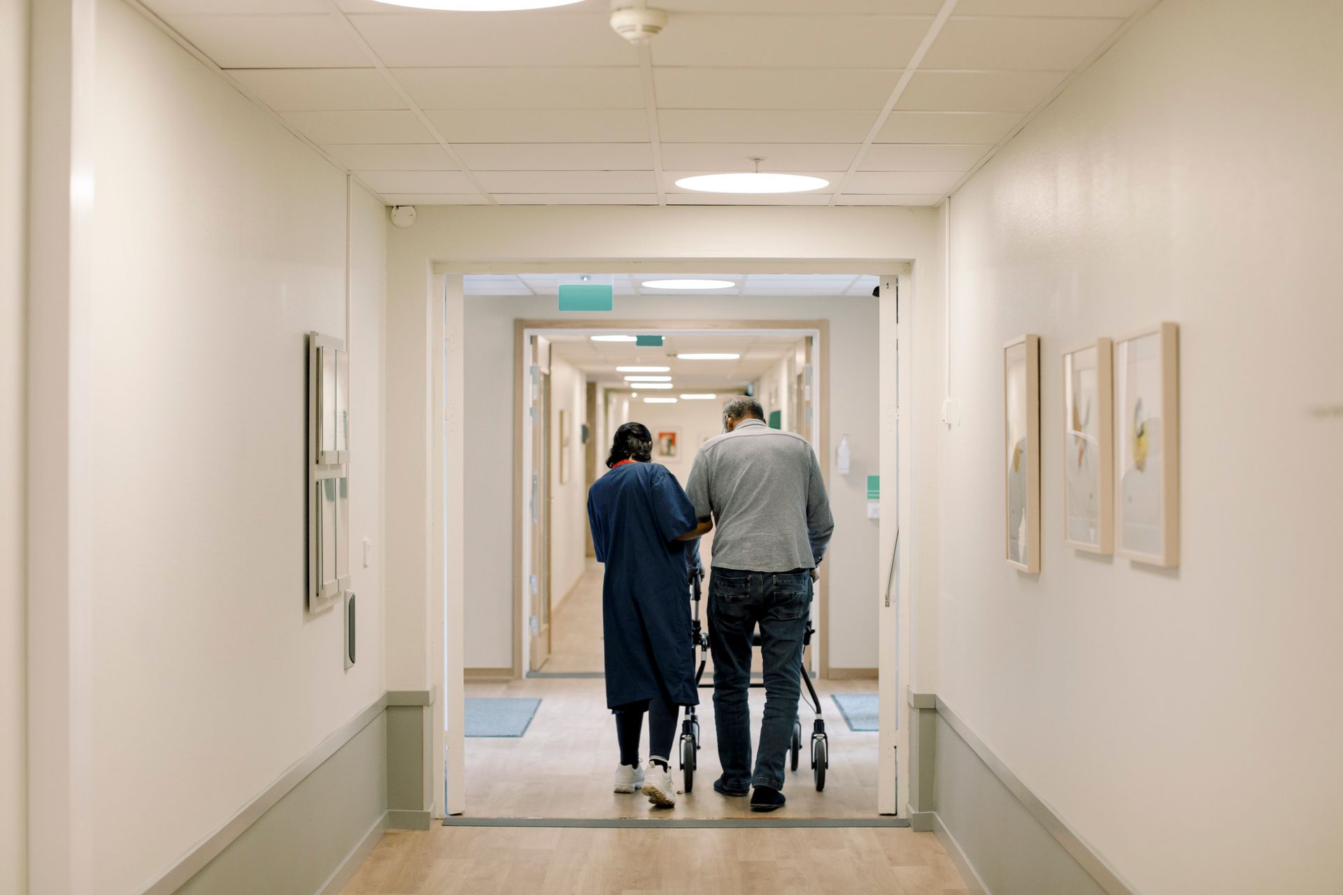 A man and a woman are walking down a hospital hallway.