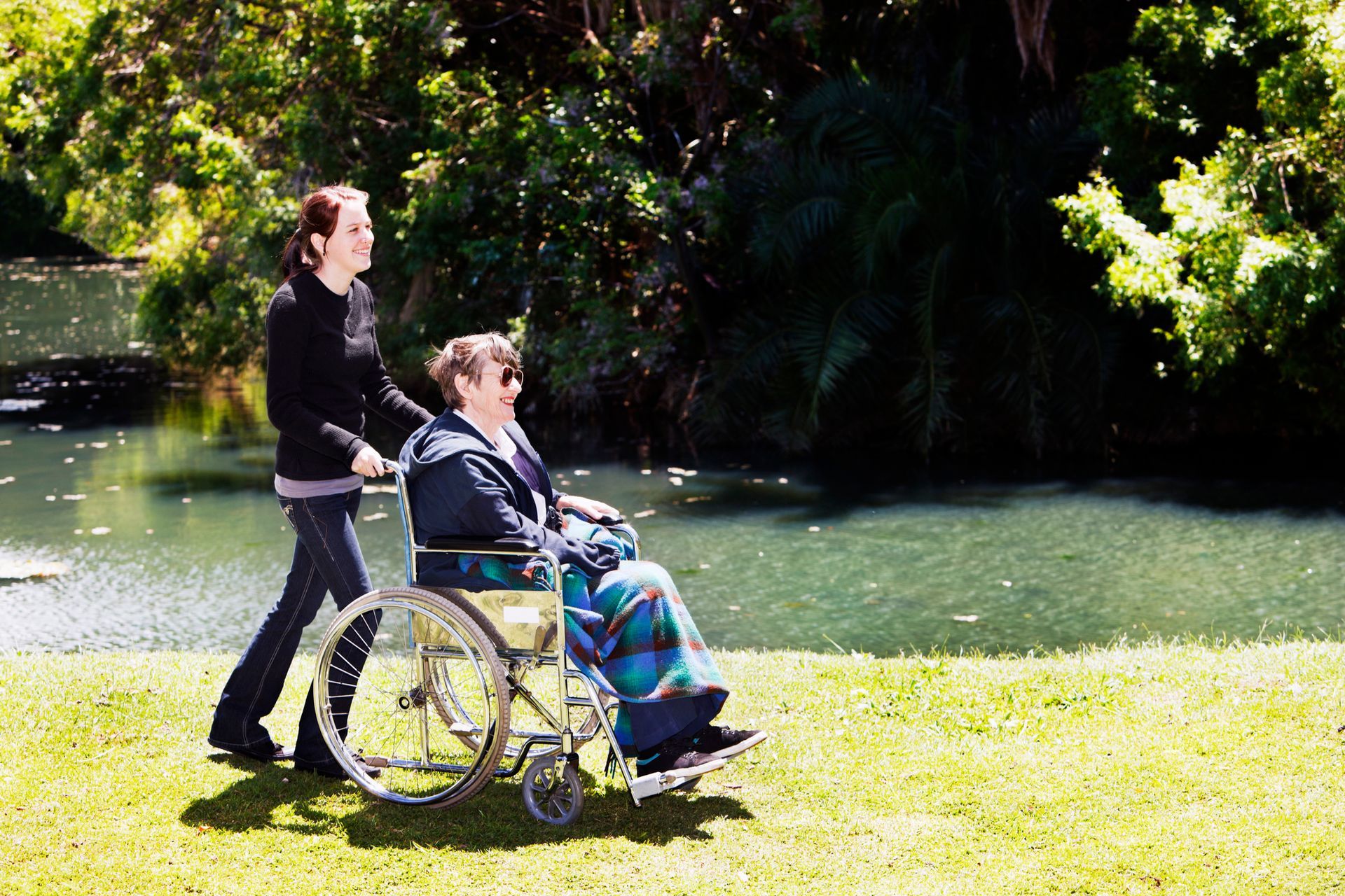 A woman pushes an elderly woman in a wheelchair