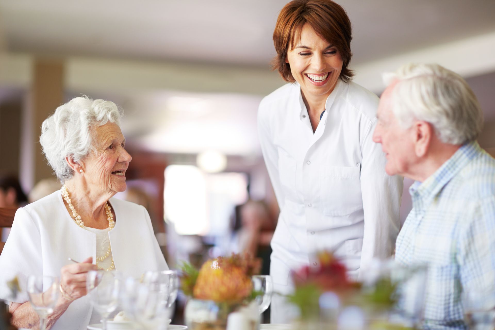 An elderly couple and a waitress are sitting at a table in a restaurant.