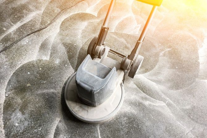 A lawn mower is being used to clean a concrete floor.