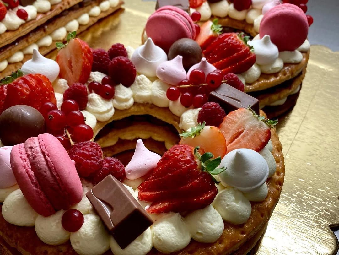 Torta di pasta sfoglia a strati decorata con crema, macarons, frutti di bosco e meringa.