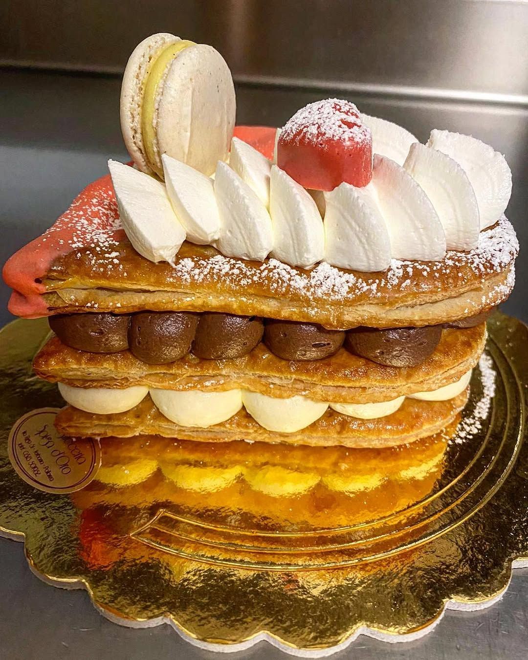 Pasta sfoglia multistrato con crema, cioccolato e frutta, guarnita con un macaron.