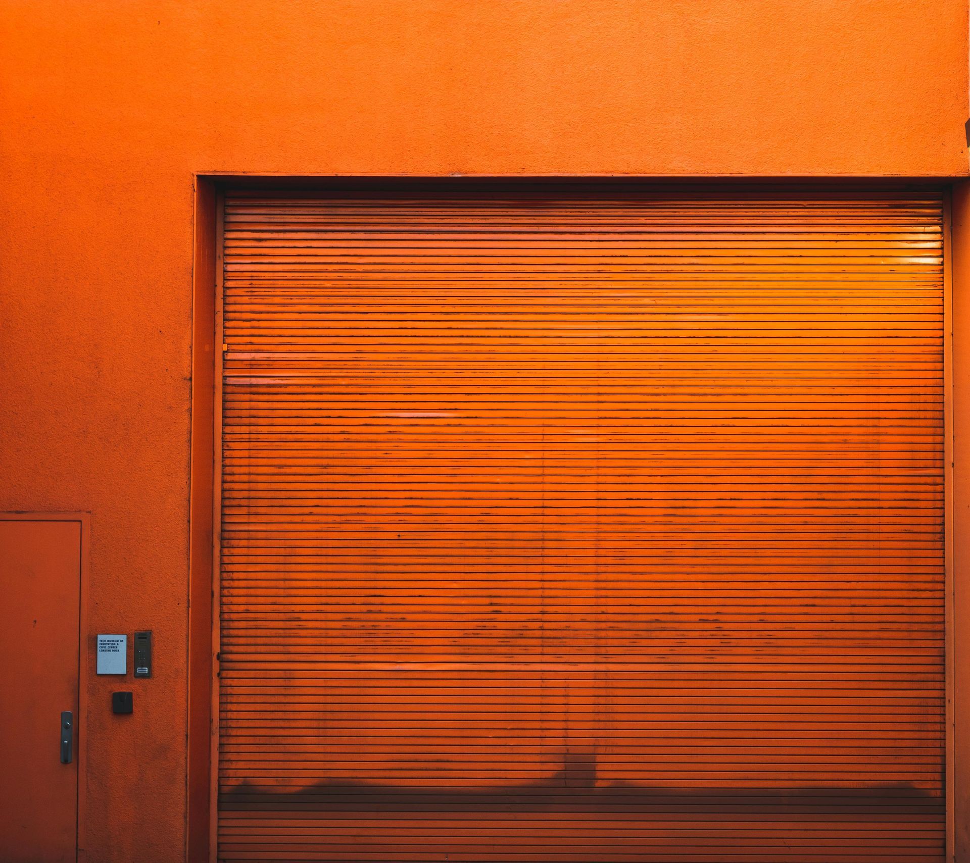A close up of an orange garage door on an orange wall.