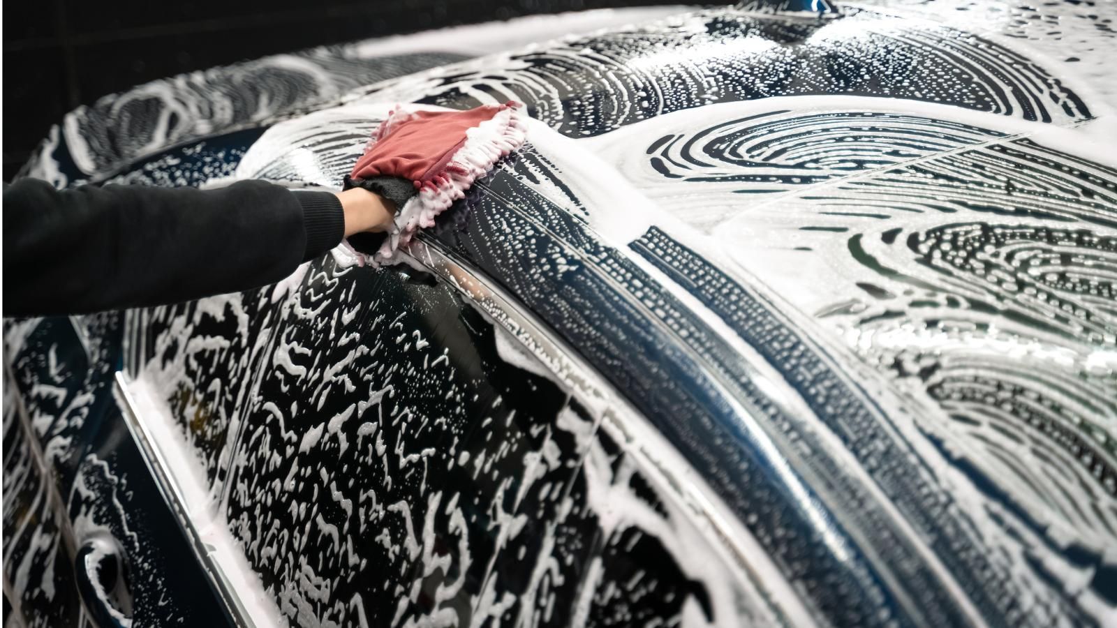 A person is washing a car with soap and water.